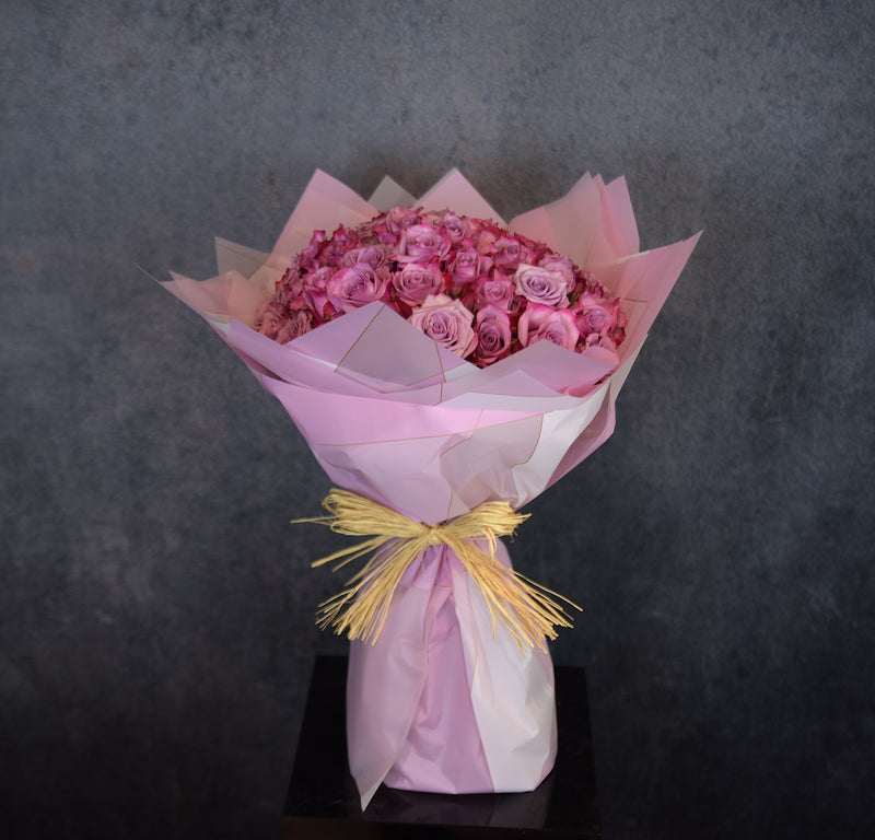 Bouquet of dark pink roses wrapped in pink